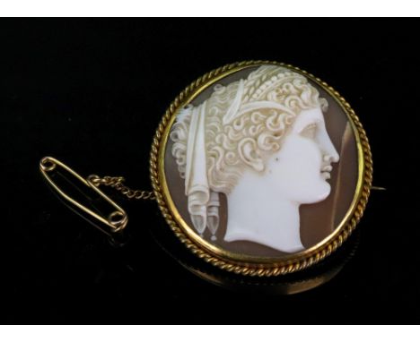 A cameo brooch, the cameo of female profile portrait within a scroll border, complete with brooch fitting and safety chain.