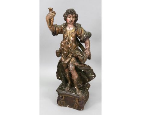 An Italian carved giltwood gesso and polychrome painted standing figure, 17th/18th century, holding a wrythen cornucopia cand