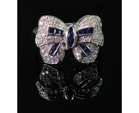 A white gold, sapphire and diamond ring, designed as a ribbon tied bow, mounted with circular cut diamonds and with calibre c