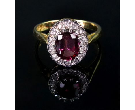 An 18ct gold pink sapphire set and diamond cluster ring, the oval gemstone claw set within a surround of semi rub over diamon