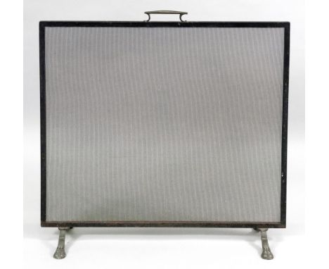 A wrought metal rectangular fireguard with brass carrying handle and paw feet, 74.5cm high x 71cm wide.