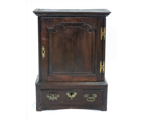 A George III oak table top cupboard, the shaped raised and fielded panel door enclosing two shelves, on a projecting rectangu