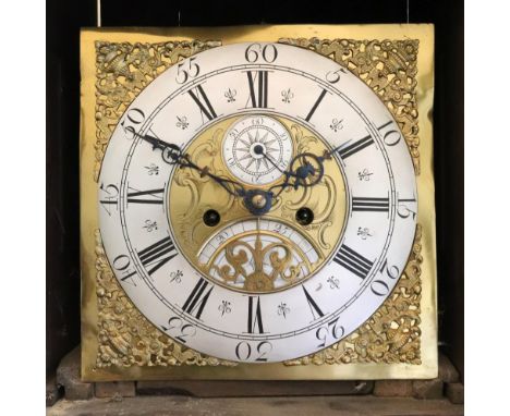 An early 18th century oak longcase clock, the hood with moulded cornice, the trunk with arched long door, on a later panelled