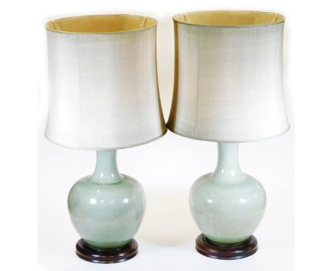 A pair of Chinese celadon porcelain lamp vases, each of bellied circular form with wooden plinths and bases with shades and m