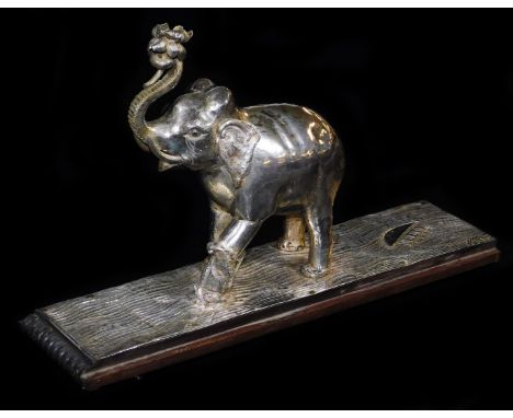 An early 20thC ceremonial figure group of an elephant being attacked by a wild beast, with trunk raised on a repousse decorat