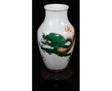 A Chinese porcelain vase, decorated with an enamel dragon, on a heavily carved wooden base, 28cm high.