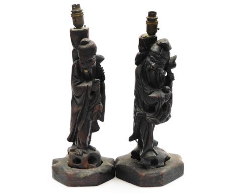 A pair of late 19th/early 20thC oriental carved hardwood lamp bases, each decorated in the form of an immortal with simulated