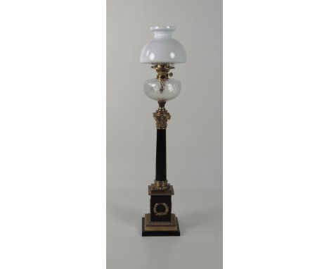 A very tall brass and black Table Oil Lamp, shaped as a Corinthian pillar with plain glass bowl and milk glass shade, on a sq