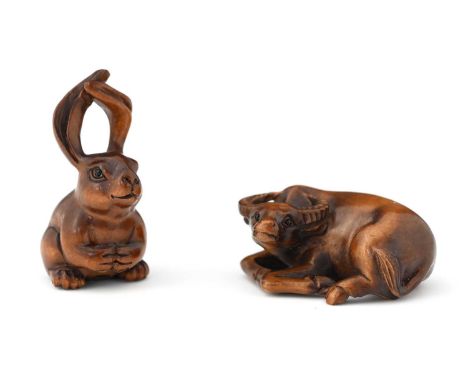 Two Japanese carved wooden netsuke, Meiji, modelled as a water buffalo and a hare, each set ith glass eyes, signed by the sam