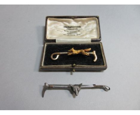 Two fox and whip stock pins, the first, stamped '15ct', with a realistically modelled running fox on a hunting whip, in a per