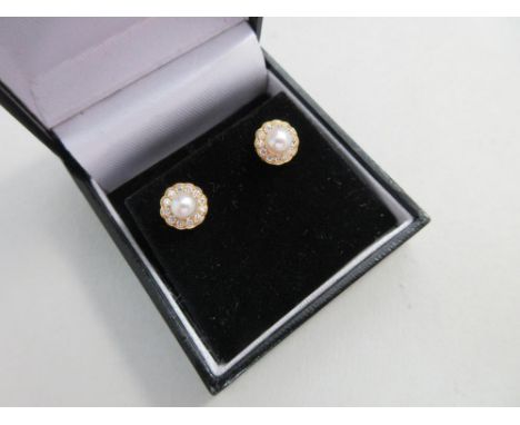 A pair of cultured pearl and diamond earstuds set in 18ct gold, each with a 4.4mm pearl above a scalloped edge border of roun