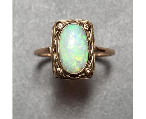 An Art Nouveau style opal ring, the oval cabochon opal collet set in a hand-crafted pierced rectangular mount with loosely tw