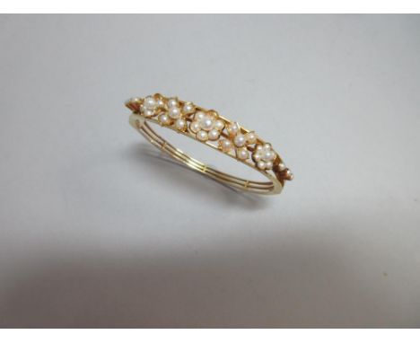 A seed pearl set hinged bangle, the three knife edge bars flaring at the front and supporting a graduated line of seed pearl 