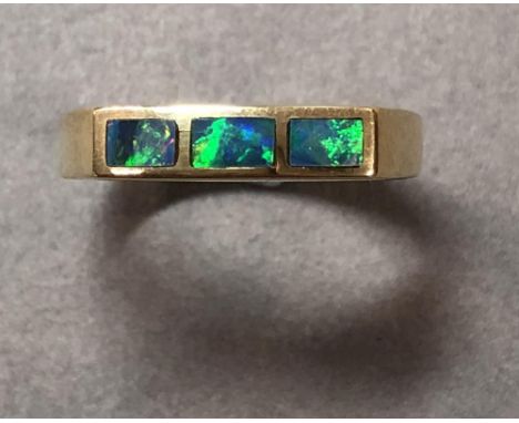 A three stone black opal ring set in 18ct gold, the narrow linear front of the ring rubover set with three rectangular black 