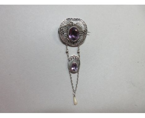 An Arts and Crafts amethyst and freshwater pearl pendant brooch, with an oval cut amethyst in an open wirework surround from 