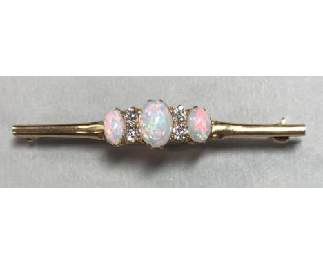 An opal and diamond seven stone bar brooch, the central arched and carved section set with three graduated oval cabochon opal