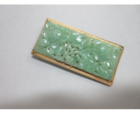 A carved jade plaque brooch, the pierced rectangular plaque depicting flowers, leaves and stems, in mottled translucent light