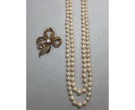 A gold and cultured pearl brooch by Andreas Daub together with a two row cultured pearl necklace, the brooch designed as a fi