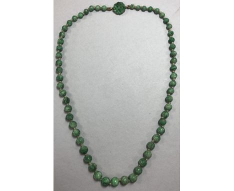 A carved jade bead necklace, the 5.5-8.5mm graduated mottled mid green jade beads, all carved and individually knotted, to a 