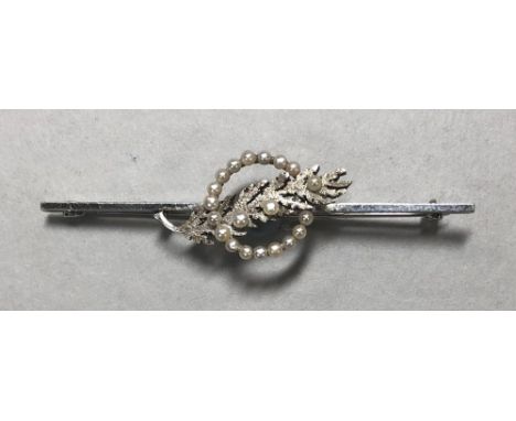 A seed pearl set bar brooch, with a central textured leaf set with three seed pearls tucked through a circlet of seventeen se