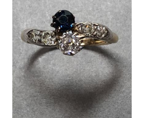 An early 20th century sapphire and diamond crossover ring, obliquely set to the centre with an old brilliant cut diamond and 