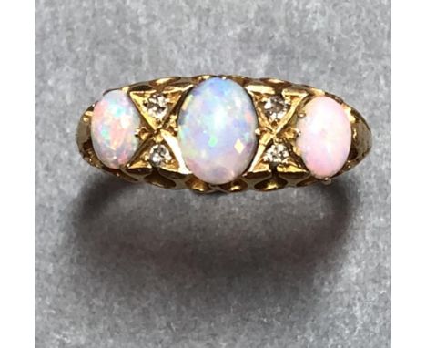 An Edwardian opal and diamond ring set in 18ct gold, the three graduated oval cabochon opals separated by X figures in which 