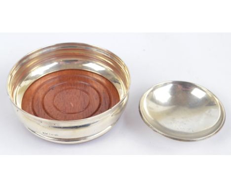 AT CANNON LTD; an Elizabeth II hallmarked silver framed bottle coaster, Sheffield 1973, diameter 10.5cm, and a circular pin d