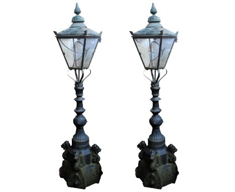 A pair of Victorian cast iron lamps, the copper upper sections with four glass angled panels with scrolling bracket and base 