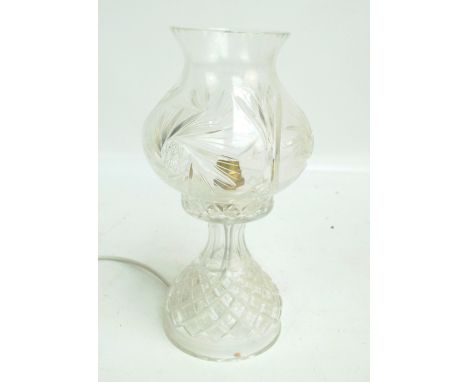 A clear cut glass table lamp with tulip shaped shade above spreading circular base, height 32cm.