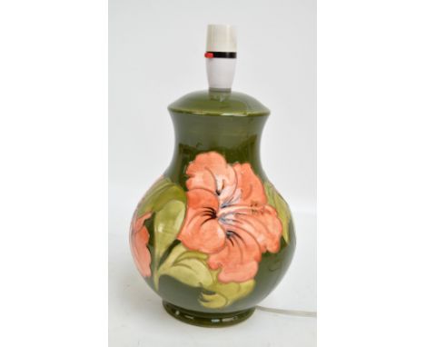MOORCROFT; a 'Hibiscus' pattern tube line decorated baluster lamp base on green ground, impressed marks and 'By Appointment P