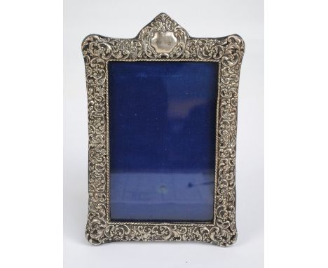 JAMES DEAKIN & SONS; a Victorian hallmarked silver foliate scroll embossed photo frame with vacant cartouche to top, with eas