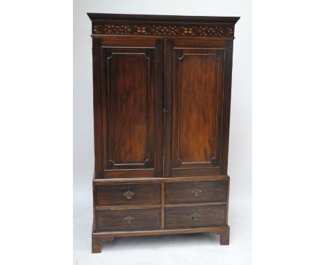 An early 20th century mahogany wardrobe converted from a linen press, the moulded dentil fretwork decorated cornice above two