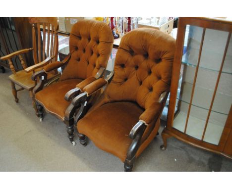 A pair of Victorian mahogany framed armchairs with button upholstered backs, scrolling arms and baluster turned front legs (o