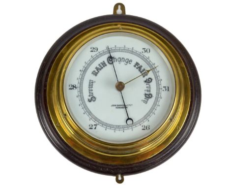A brass cased porthole wall aneroid barometer on turned circular wooden mount, retailer's mark 'John Barker & Co Ltd, Kensing