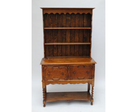 A small oak dresser with boarded plate rack, two deep drawers and shaped potboard base.   CONDITION REPORT:  The colour has f