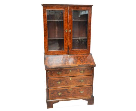 An early 18th century walnut bureau bookcase, the upper section with two glazed doors enclosing shelves above a base with fal