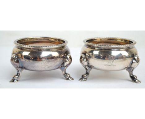 A pair of George II hallmarked silver circular open salts with cast rims and gilt wash interiors, raised on three outswept le