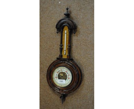 An early 20th century carved walnut framed wheel barometer beneath thermometer, length 56cm.