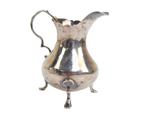 WILLIAM KERSILL; a George II hallmarked silver cream jug of baluster form with shaped rim and S-scroll handle, raised on thre