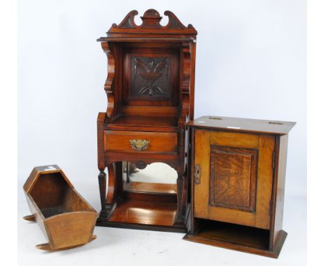 An early 20th century oak smoker's cabinet, with hinged top and single door enclosing compartmentalised interior with pipe ra