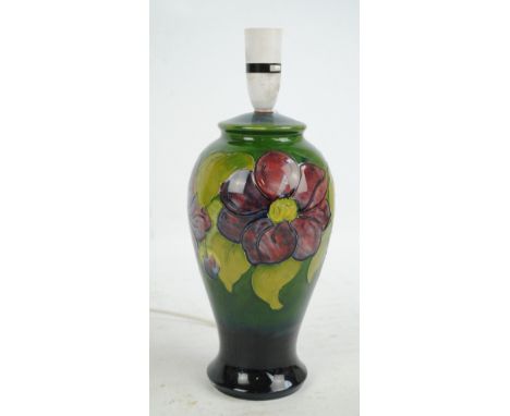 MOORCROFT; a 'Clematis' pattern tube line decorated baluster lamp base on green ground, impressed marks to base, height 27.5c