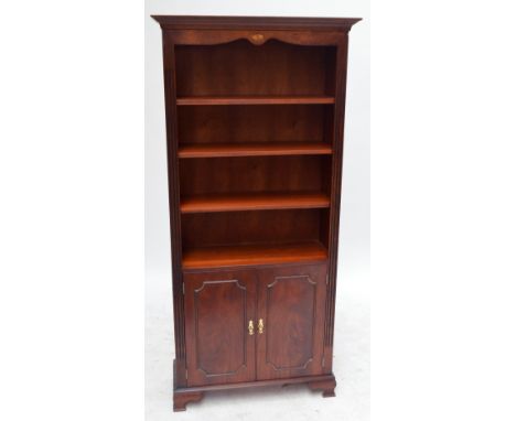 A reproduction mahogany open bookcase with four shelves above pair of doors, on ogee bracket feet, height 184cm, width 78.5cm