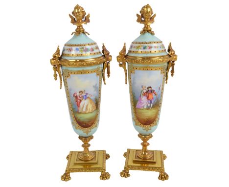 A pair of late 19th century Continental gilt metal mounted and gilt heightened porcelain urns, each surmounted with a winged 