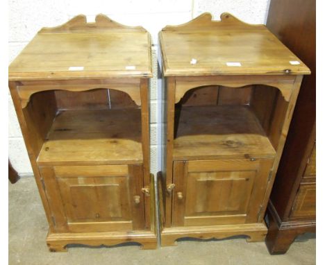 A pair of stained pine bedside cupboards, each fitted with a single door below a shelf, 41.5cm wide, 82cm high, (2).