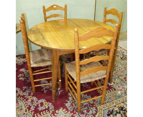 A pine circular table on square tapered splayed legs, 119.5cm diameter and a set of four pine ladder-back rush-seated chairs.