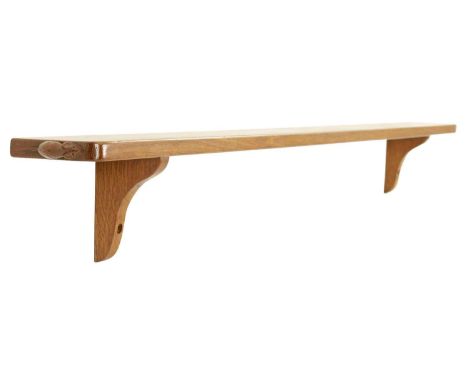 A ROBERT ‘MOUSEMAN’ THOMPSON AZED OAK SHELF with shaped brackets and signature carved mouse motif.144cm wide 11.5cm deep 16cm