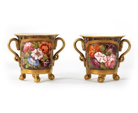 A PAIR OF EARLY 19TH CENTURY DUESBURY DERBY TWO-HANDLED CUPS RAISED ON CLAW AND BALL FEET Royal Blue ground and richly embell