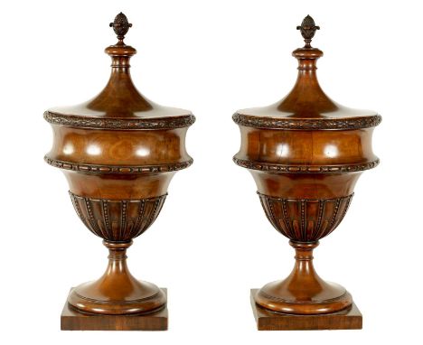 A FINE PAIR OF LATE 19TH CENTURY MAHOGANY LIDDED URNS with flower head carved banding above tapering gadrooned bodies, standi