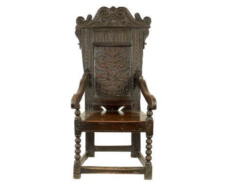 A 17TH CENTURY OAK WAINSCOT CHAIR with shaped carved cresting above a branchwork panel, shaped sweeping arms above a plank se