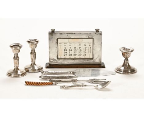 A silver mounted desk calendar, together with a pair of silver candlesticks, a single candlestick and various pieces of cutle